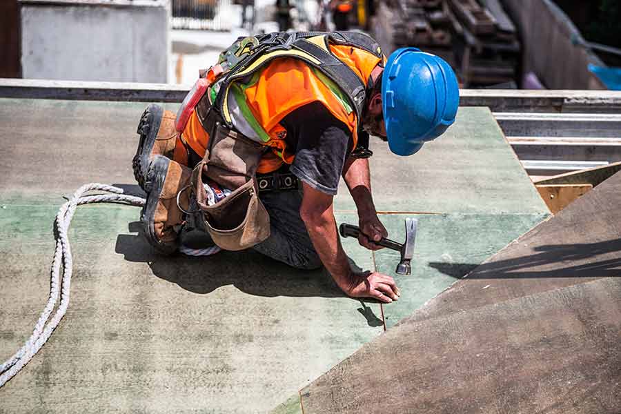 man-wearing-blue-hard-hat-using-hammer