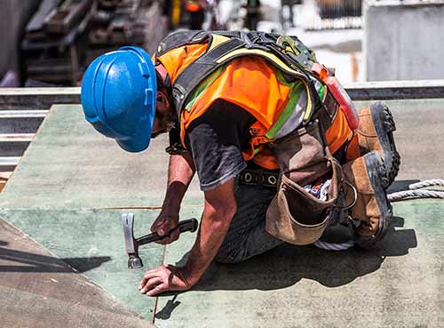 man-wearing-blue-hard-hat-using-hammer